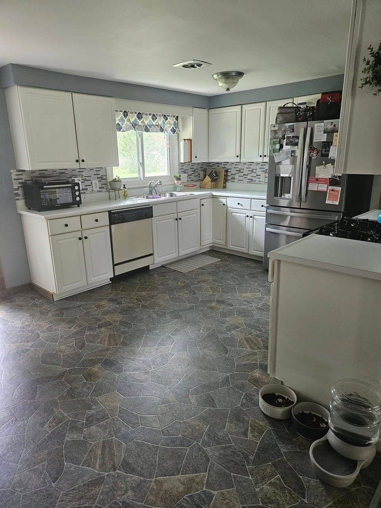 Spotless white kitchen with stone-pattern floor after a cleaning visit